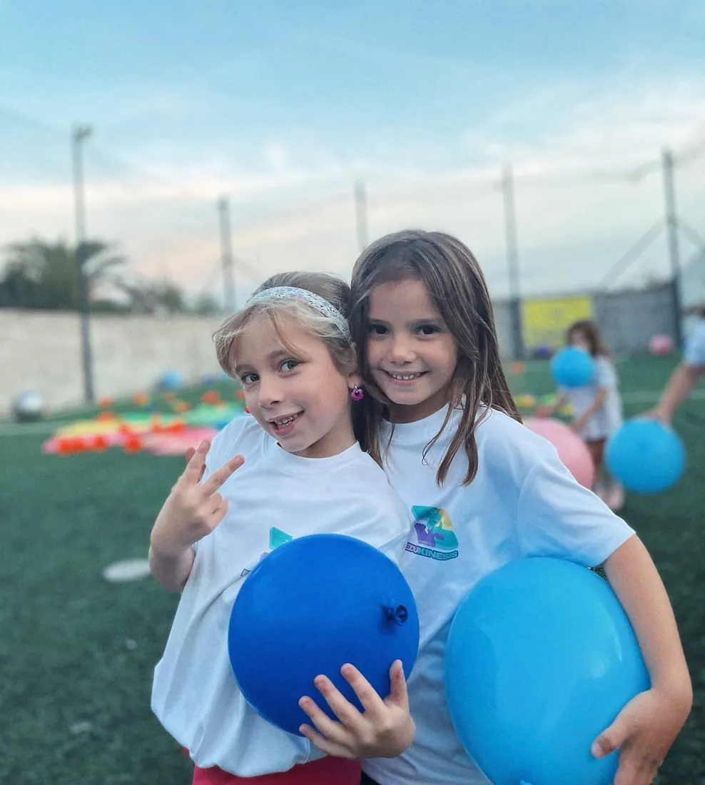 Dos niños sonrientes con globos azules en una actividad recreativa